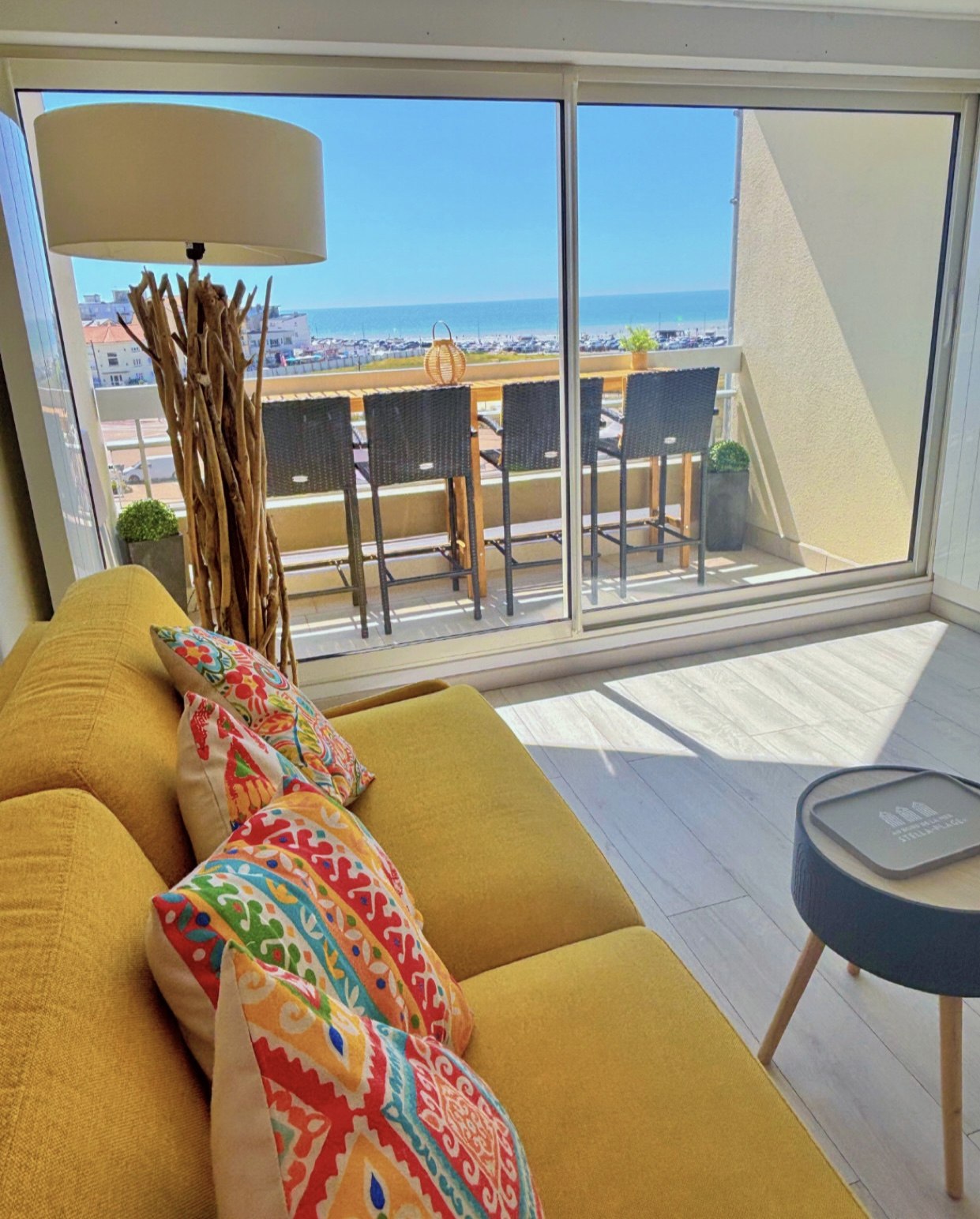 Salon du duplex avec canapé jaune et baie vitrée donnant sur le balcon vue mer